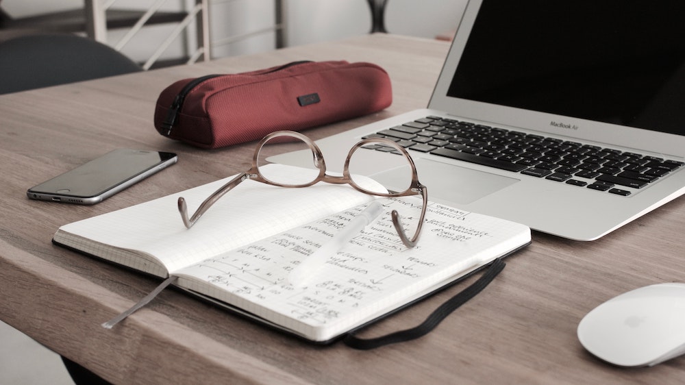 eye glasses on a desk in front of a computer