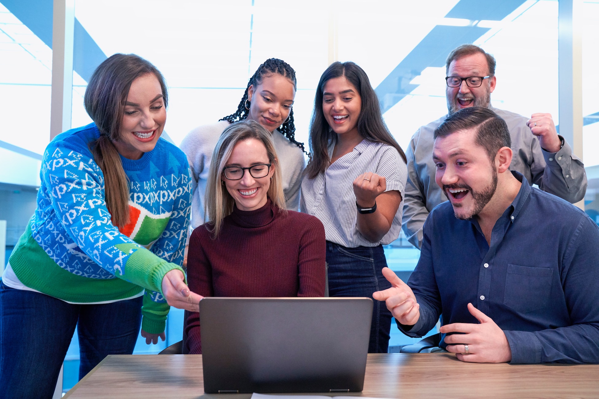 A team of people around a laptop