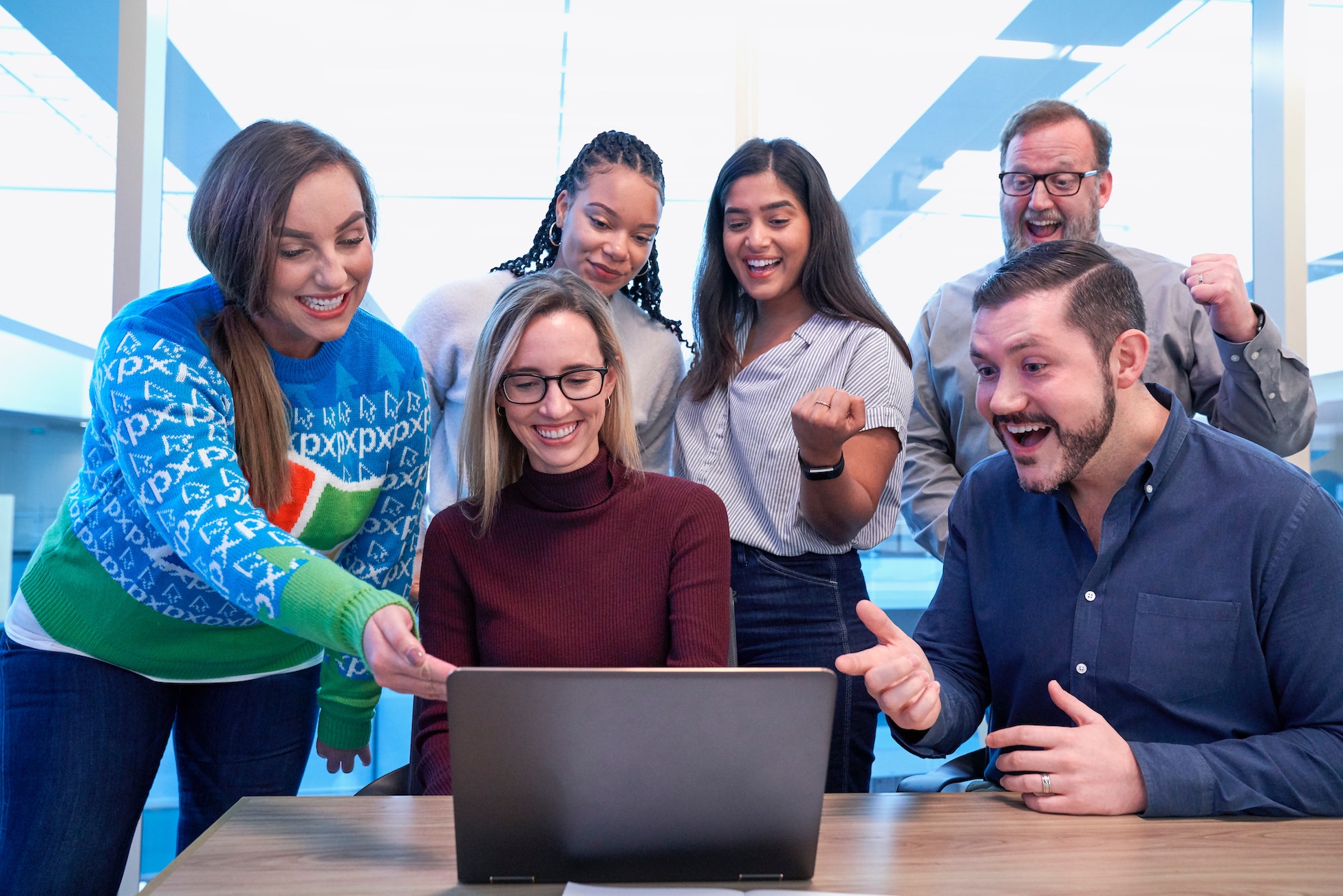 A team of people around a laptop